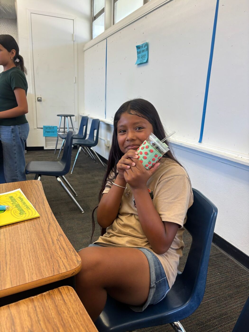 A smiling camper at her desk with her Money Maze workbook