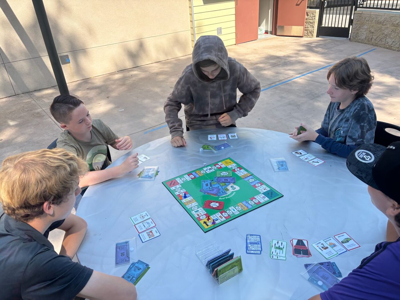 Students playing Dollars and Decisions at a round table outdoors
