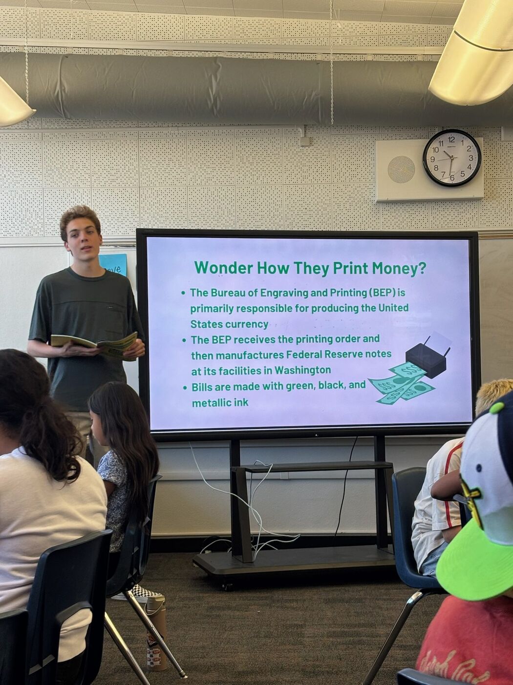 A founder teaching a lesson from the screen at the front of a classroom