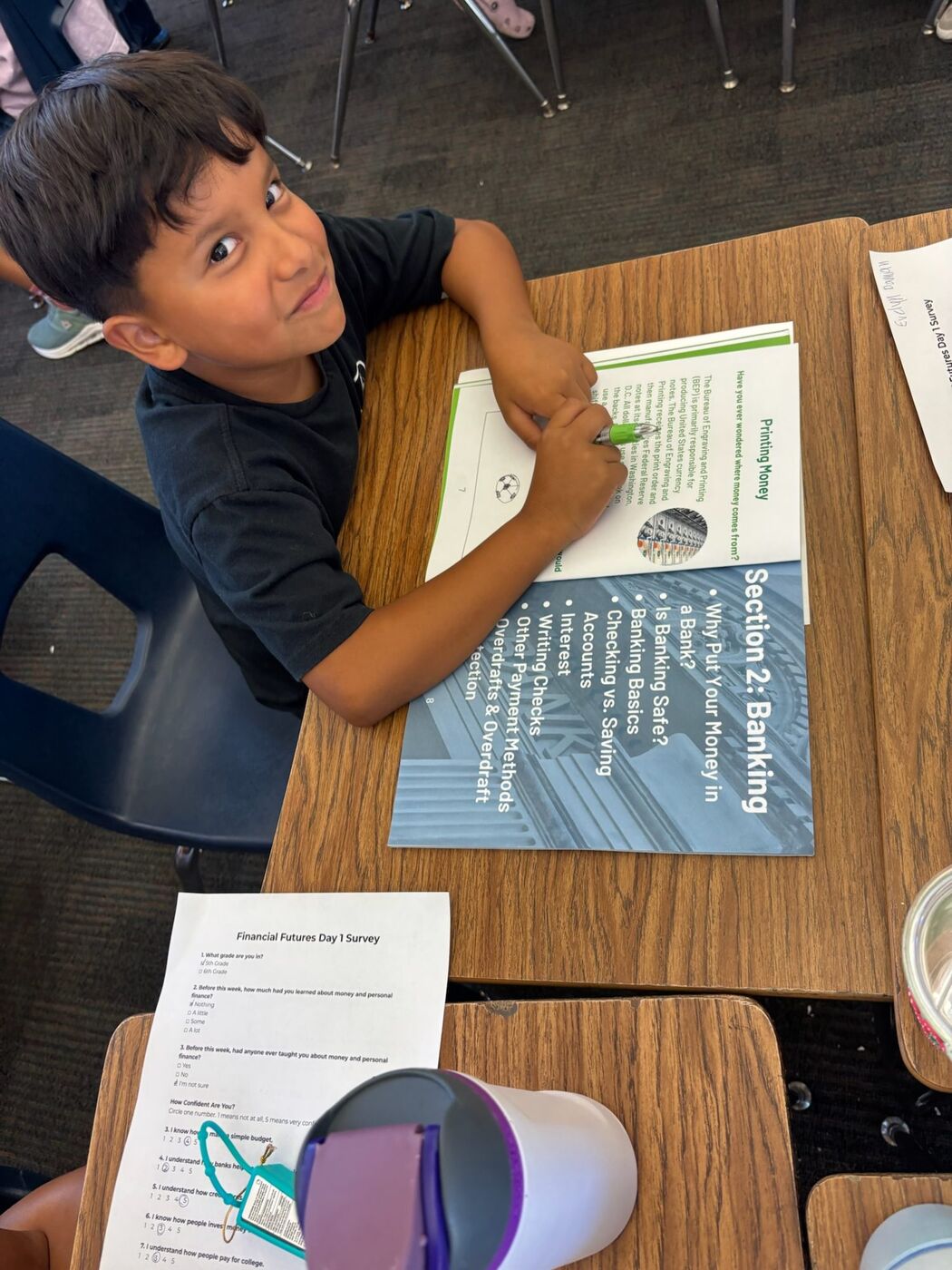A camper grinning over his shoulder with his workbook open to the banking section